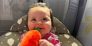 Aoibhí joined the competition — help win amazing prizes! baby, child, plush_toy, carrot, pink_clothing, onesie, playpen, toy, smiling, happy, indoor, cute, infant, face, sitting, baby_girl, patterned_clothing, soft_toy, play_area, decorative_background