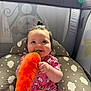 baby, child, plush_toy, carrot, pink_clothing, onesie, playpen, toy, smiling, happy, indoor, cute, infant, face, sitting, baby_girl, patterned_clothing, soft_toy, play_area, decorative_background