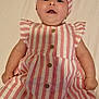 baby, infant, child, dress, headband, bow, striped_clothing, pink, white, smiling, lying_down, cute, buttoned_dress, indoors, skin, happy, young_child, portrait, one_person, headwear