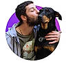 Biancka participe au concours pour gagner de l'argent avec cette photo : man, dog, kiss, affection, portrait, pet, animal, canine, beard, casual_clothing, chain_necklace, black_dog, brown_markings, collar, hand, human, love, closeup, purple_background, circle