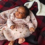 Brielle is registered to the contest to win money with this photo: baby, infant, pink_dress, tulle, gold_spots, curly_hair, blanket, checkered, red, black, feet, hands, face, portrait, cute, child, cozy, indoor, soft_light, resting
