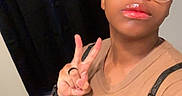 Yoda is registered to the contest to win money with this photo: person, glasses, peace_sign, cat, indoor, floor, curtain, tshirt, lipstick, hand, brown_skin, short_hair, watch, ring, selfie, casual, background, text_overlay, blue_reflection, brown_cat