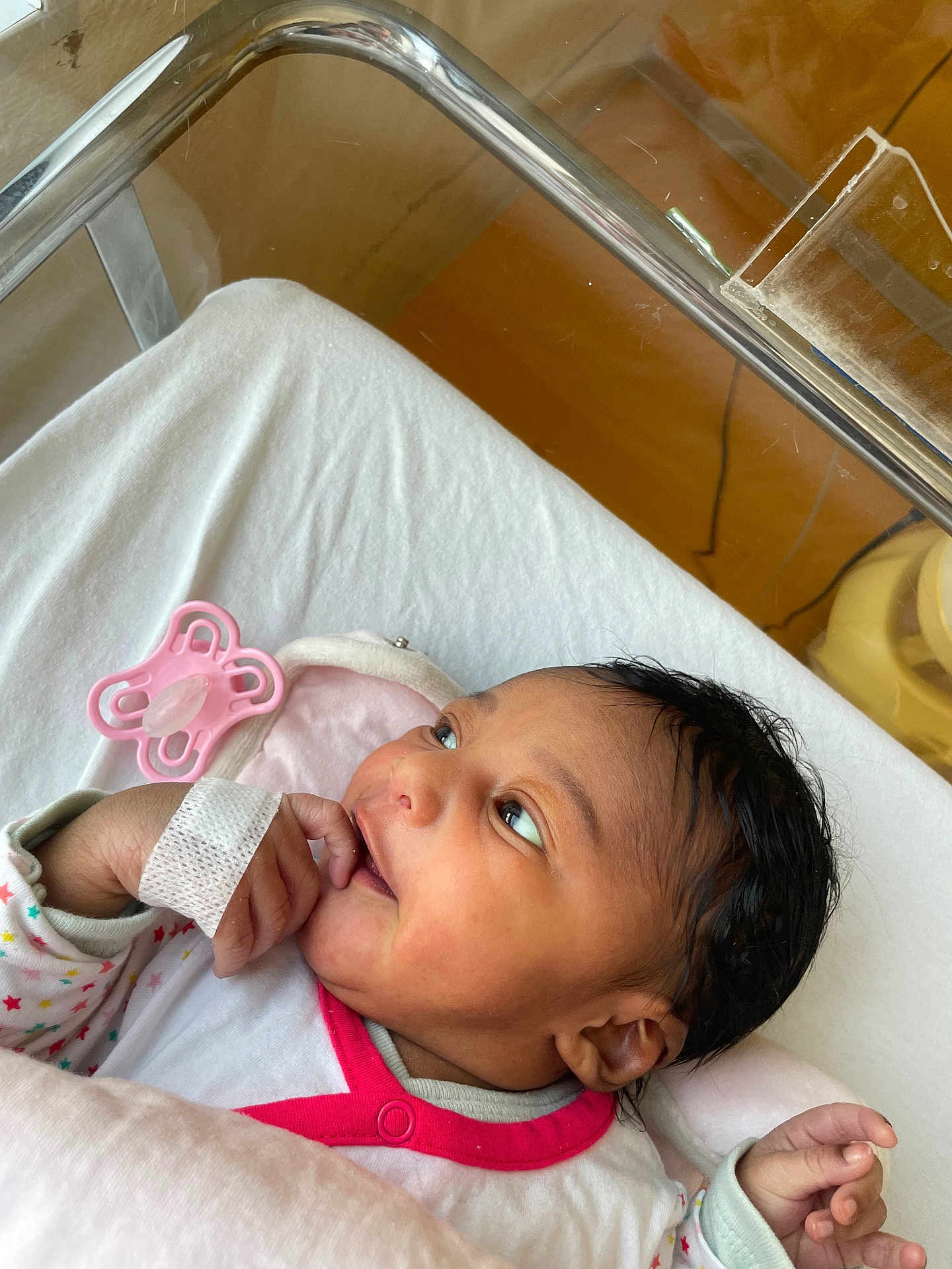 Lou-Eva a rejoint le concours — aidez-le/la à gagner de superbes lots ! baby, newborn, hospital, crib, infant, pacifier, hand, face, clothing, wristband, lying, cute, curious, pink, white, star_pattern, sleepwear, skin, person, indoors