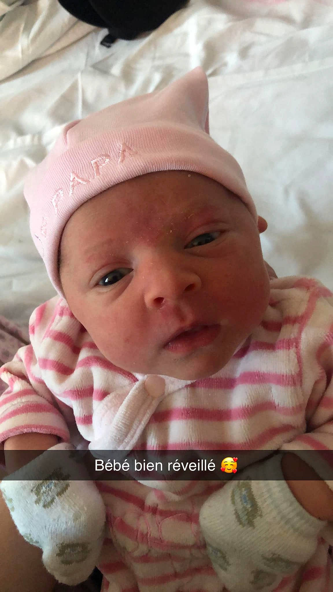 Emma participe au concours pour gagner de l'argent avec cette photo : baby, baby_products, baby_safety, baby_toddler_clothing, cap, cheek, child, comfort, fun, happy, headgear, headwear, linens, lip, mouth, nose, person, pink, skin, smile