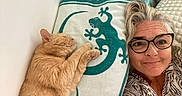 Léo participe au concours pour gagner de l'argent avec cette photo : cat, orange_cat, woman, face, glasses, smiling, sleeping, cuddling, pet, selfie, portrait, indoors, bed, pillow, blanket, cozy, home, feline, relaxed, patterned_fabric