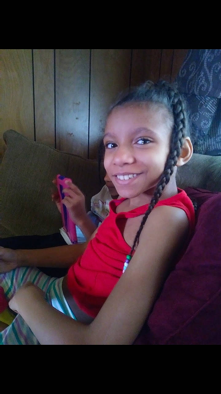 Saniyah is registered to the contest to win money with this photo: beauty, cheek, child, chin, day, eye, eyebrow, face, forehead, girl, hair, hairstyle, head, human_hair_color, joy, nose, person, purple, sitting, skin