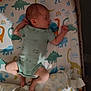 Estella is registered to the contest to win money with this photo: baby, newborn, sleeping, onesie, pacifier, blanket, teddy_bear_pattern, dinosaur_pattern, crib, mattress, infant, child, cute, peaceful, indoors, soft_lighting, resting, small, wearing_clothes, person