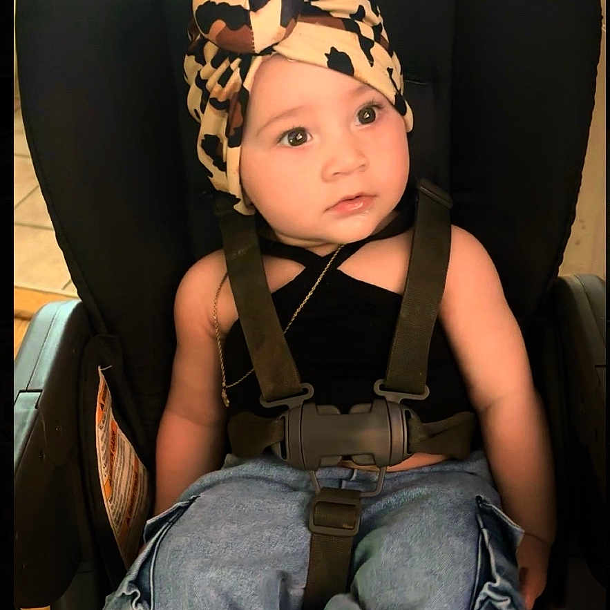 Kiari Chanel is registered to the contest to win money with this photo: child, toddler, baby, car_seat, sitting, portrait, face, eyes, looking_up, curious, cow_print, hat, shoes, jeans, cargo_pants, seatbelt, indoors, vehicle, fashion, smiling