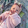 adorable, baby, blanket, blue_eyes, child, clothing, cozy, cute, face, hand_near_mouth, headband, infant, knitted, lying_down, outdoor, patterned_blanket, pink_sweater, portrait, soft_lighting, young_child
