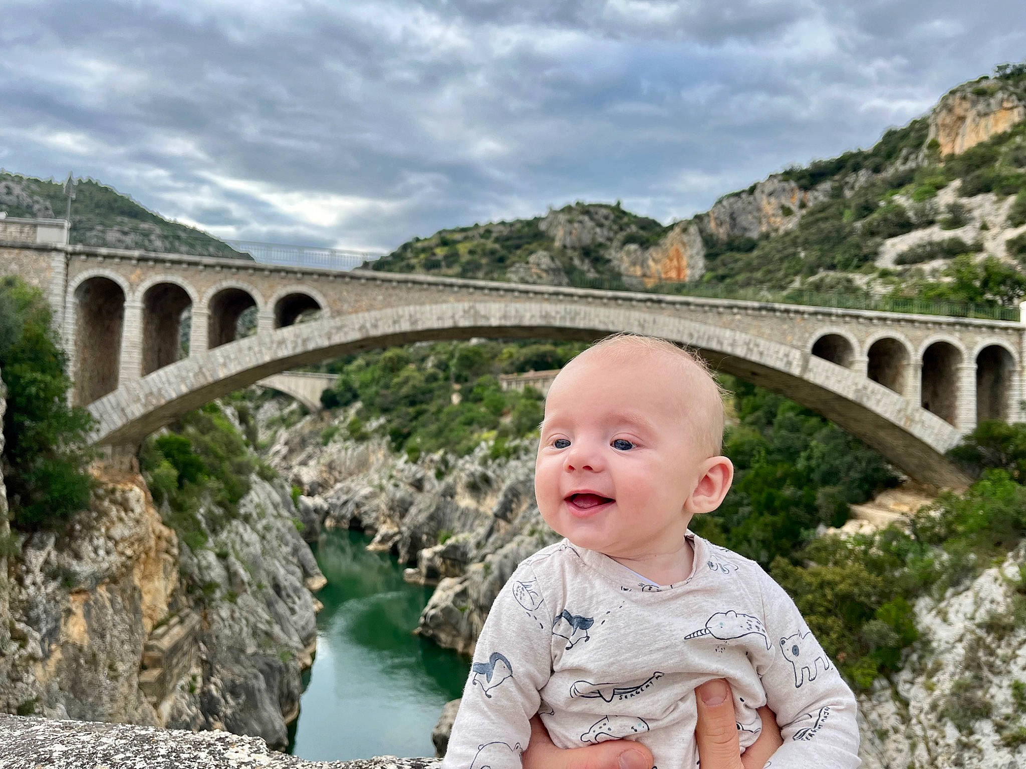 Hugo a rejoint le concours — aidez-le/la à gagner de superbes lots ! aqueduct, arch, arch_bridge, baby, baby_toddler_clothing, bridge, cloud, happy, landscape, leisure, mountain, person, plant, reservoir, sky, smile, toddler, tourism, travel, tree