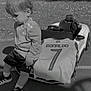 Liam a rejoint le concours — aidez-le/la à gagner de superbes lots ! toddler, child, toy_car, football_jersey, ronaldo, number_7, outdoor, grass, trees, pavement, sportswear, sneakers, shorts, jacket, seat, car, small_vehicle, name_tag, portrait, daylight