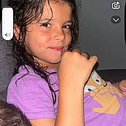 Victoire a rejoint le concours — aidez-le/la à gagner de superbes lots ! child, smiling, indoor, purple_shirt, wet_hair, couch, thumbs_up, casual, portrait, young, person, relaxed, playful, face, gesture, seated, home, comfortable, expression, dark_background