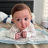 baby, bed, bedding, bedroom, blanket, child, close_up, daylight, eyes, face, hands, indoor, infant, long_sleeves, lying_down, portrait, pouting, tummy_time, white_clothing, wide_eyed