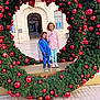 Madison participe au concours pour gagner de l'argent avec cette photo : child, children, wreath, christmas, holiday, ornaments, red_balls, festive, outdoor, bench, building, arch, smiling, curly_hair, jacket, sneakers, pavement, decoration, happy, public_place