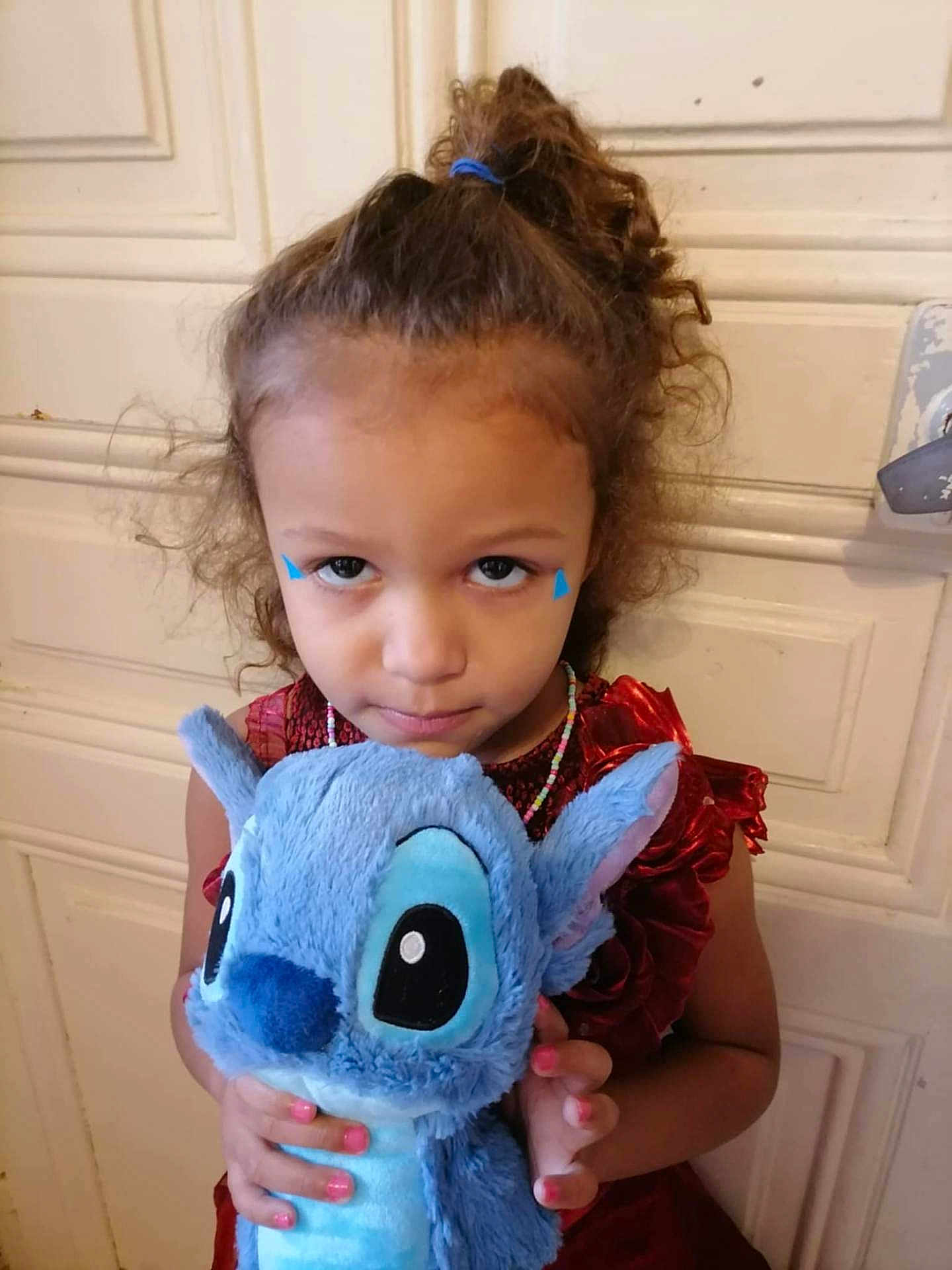 Madison a rejoint le concours — aidez-le/la à gagner de superbes lots ! child, girl, plush_toy, stuffed_animal, blue, curly_hair, red_dress, beaded_necklace, indoor, door, portrait, holding, toy, face_paint, serious, young, person, cute, hair_tie, close_up