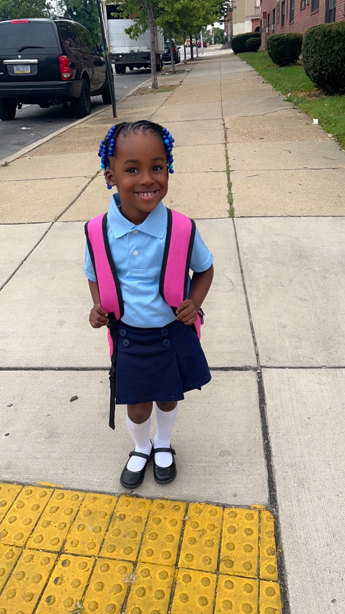 Morgan is registered to the contest to win money with this photo: asphalt, automotive_lighting, automotive_tire, black, car, cool, footwear, hairstyle, happy, head, infrastructure, joy, person, recreation, road_surface, school_uniform, shoe, sidewalk, smile, tire