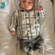 Eliot a rejoint le concours — aidez-le/la à gagner de superbes lots ! baby, infant, plaid_shirt, gray_pants, white_socks, towel, pacifier_clip, lying_down, indoors, curious_expression, child, young, cute, soft_texture, casual_clothing, small_hands, wide_eyes, head, face, resting