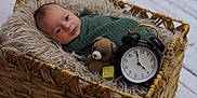 Oakley is registered to the contest to win money with this photo: baby, newborn, basket, blanket, crocheted_toy, teddy_bear, wooden_block, alarm_clock, face, infant, cozy, woven, furniture, floor, soft_texture, portrait, wrapped, cute, indoor, sleepy