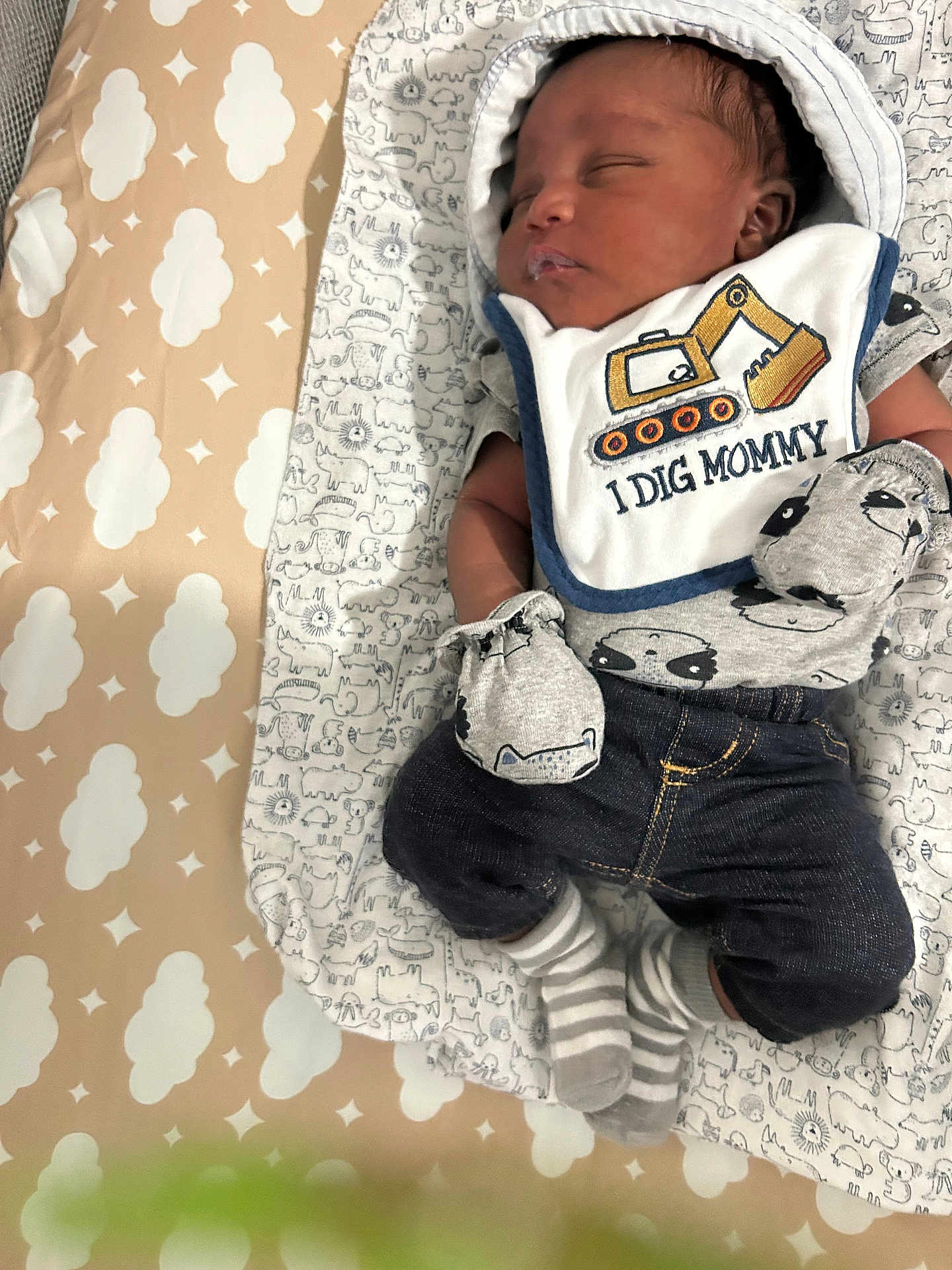 Titan is registered to the contest to win money with this photo: baby, sleeping, mittens, striped_socks, bib, construction_vehicle, blanket, patterned_blanket, cute, infant, clothing, cozy, peaceful, closeup, indoors, child, newborn, portrait, soft_lighting, resting