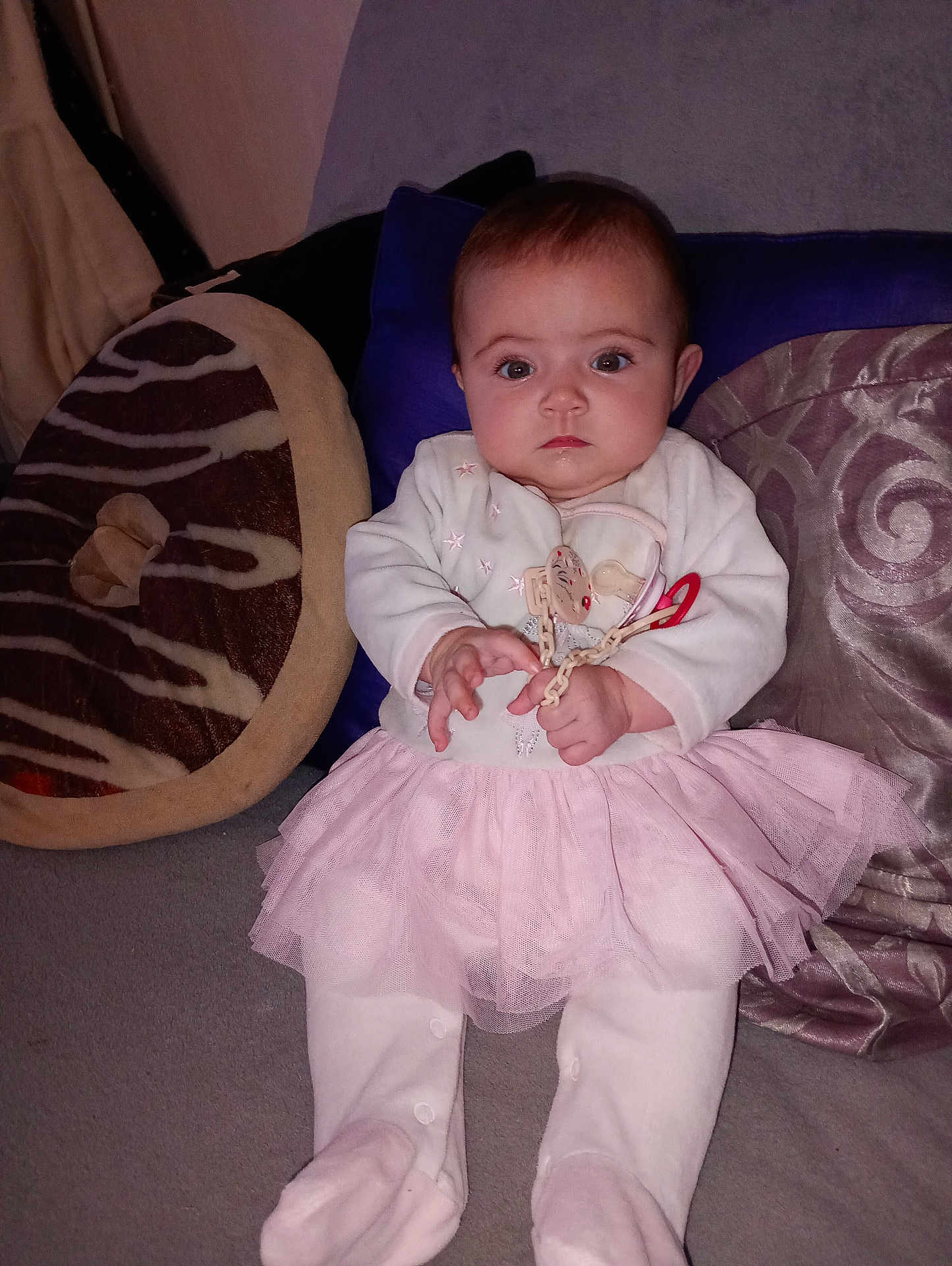 Amalya Jeanvrain a rejoint le concours — aidez-le/la à gagner de superbes lots ! baby, baby_clothes, child, cozy, cushion, cute, donut_pillow, expression, face, home, indoor, infant, pacifier, person, pillow, pink_tutu, portrait, sitting, soft_fabric, white_clothing