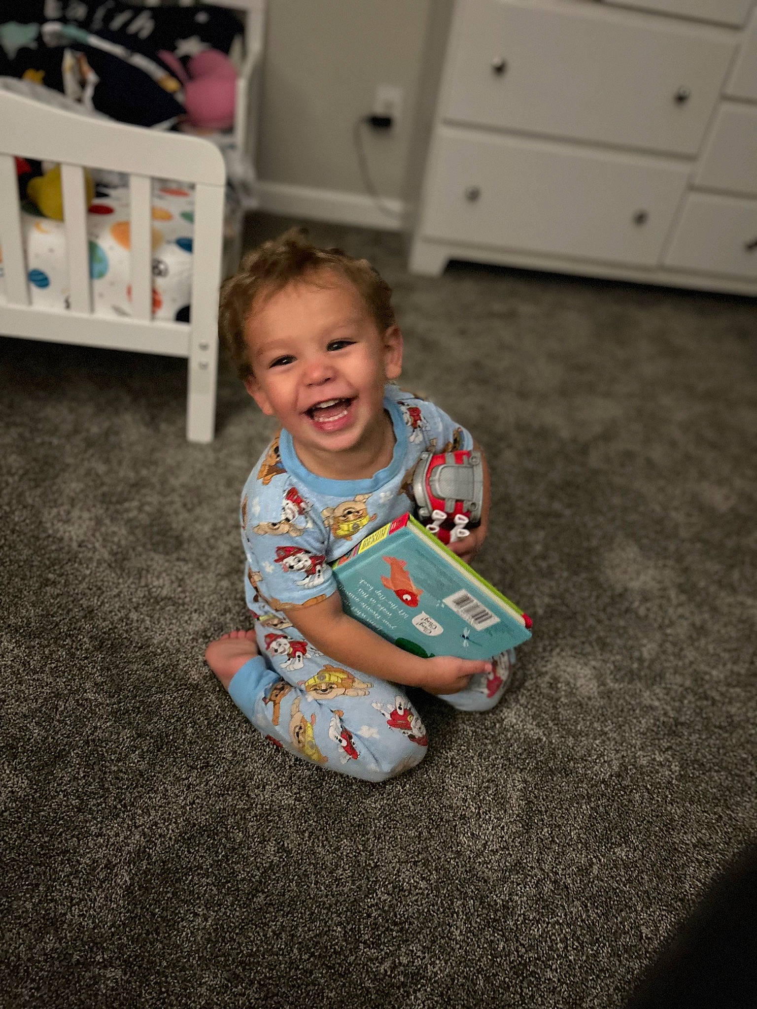 Adarien is registered to the contest to win money with this photo: baby, baby_toddler_clothing, cabinetry, chest_of_drawers, drawer, floor, flooring, fun, happy, hardwood, joy, person, room, shelf, sitting, sleeve, smile, standing, t_shirt, toddler