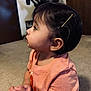 toddler, child, indoor, carpet, peach_shirt, bracelet, hairpin, earrings, profile, curious, young_child, person, casual_clothing, floor, brown_hair, small_hands, ear, expression, side_view, home