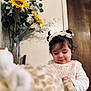 toddler, child, girl, indoor, plush_toy, sunflower, flower, hair_bow, pigtails, white_clothing, knitwear, furniture, wooden_door, vase, greenery, soft_focus, portrait, cute, playing, happy