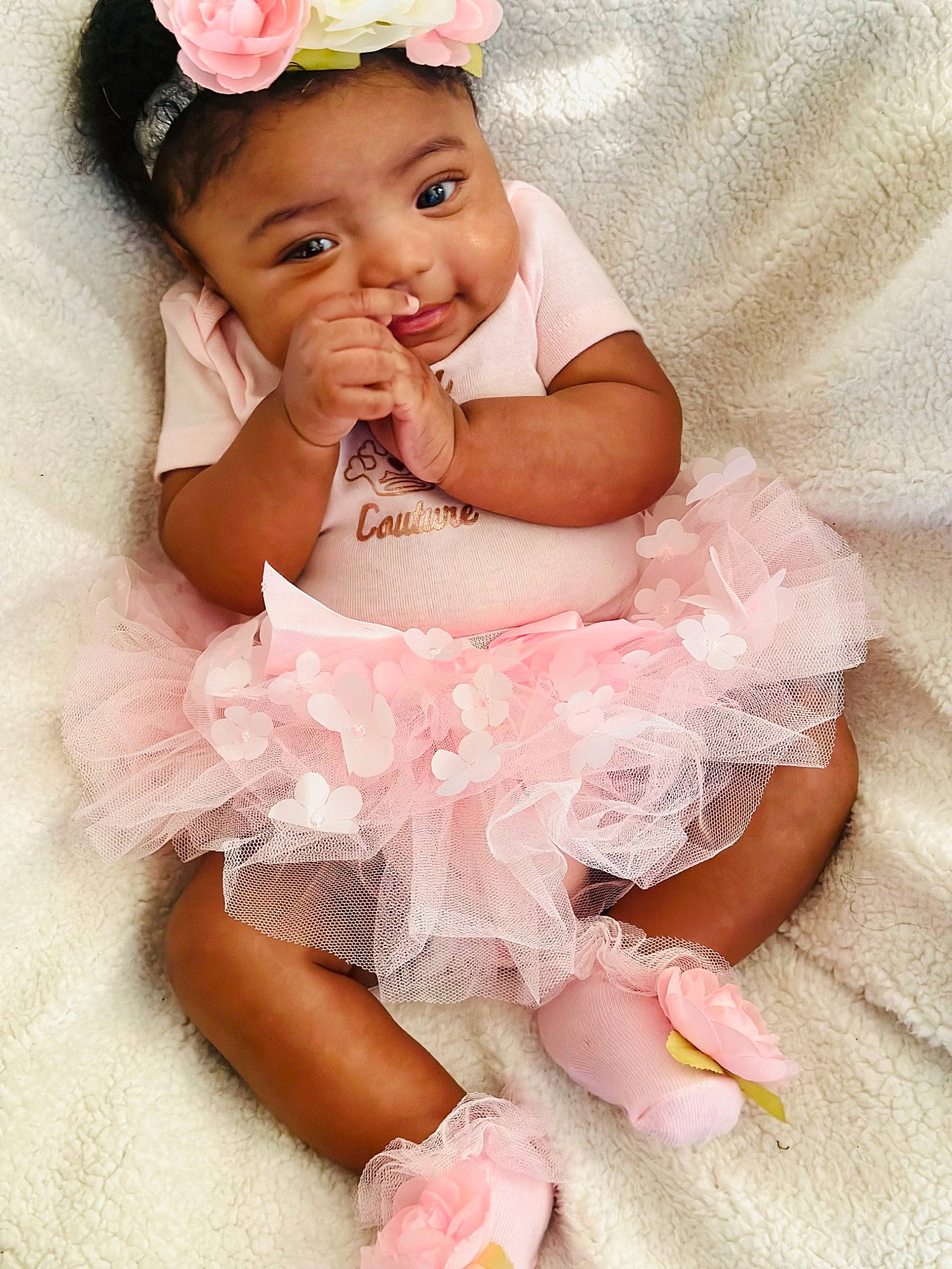 Ari is registered to the contest to win money with this photo: arm, baby, baby_toddler_clothing, child, dress, embellishment, face, finger, flash_photography, gesture, happy, headband, headpiece, jewellery, person, petal, pink, skin, smile, toddler