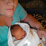 Stormi joined the competition — help win amazing prizes! adult, baby, blanket, blue_shirt, cradle, face, female, hand, indoor, newborn, person, portrait, skin, sleeping, tattoo, teddy_bear, wrapped, young_child, love, comfort