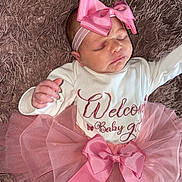 Zhavia is registered to the contest to win money with this photo: baby, infant, sleeping, pink_bow, tutu, headband, blanket, onesie, text_on_clothing, cute, newborn, soft_texture, resting, adorable, portrait, child, peaceful, close_up, toddler, celebration