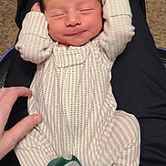 Elijah joined the competition — help win amazing prizes! baby, infant, sleeping, onesie, footwear, dinosaur_slippers, carpet, hand, lap, person, relaxing, cozy, cute, sleep, patterned_clothing, indoor, comfort, child, newborn, soft