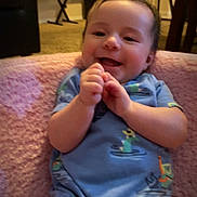 Elijah is registered to the contest to win money with this photo: baby, infant, smile, clapping, blue_onesie, duck_pattern, dinosaur_pattern, pink_blanket, indoor, living_room, carpet, chair, piano, furniture, happy, cute, child, person, portrait, home