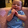 baby, infant, smile, clapping, blue_onesie, duck_pattern, dinosaur_pattern, pink_blanket, indoor, living_room, carpet, chair, piano, furniture, happy, cute, child, person, portrait, home
