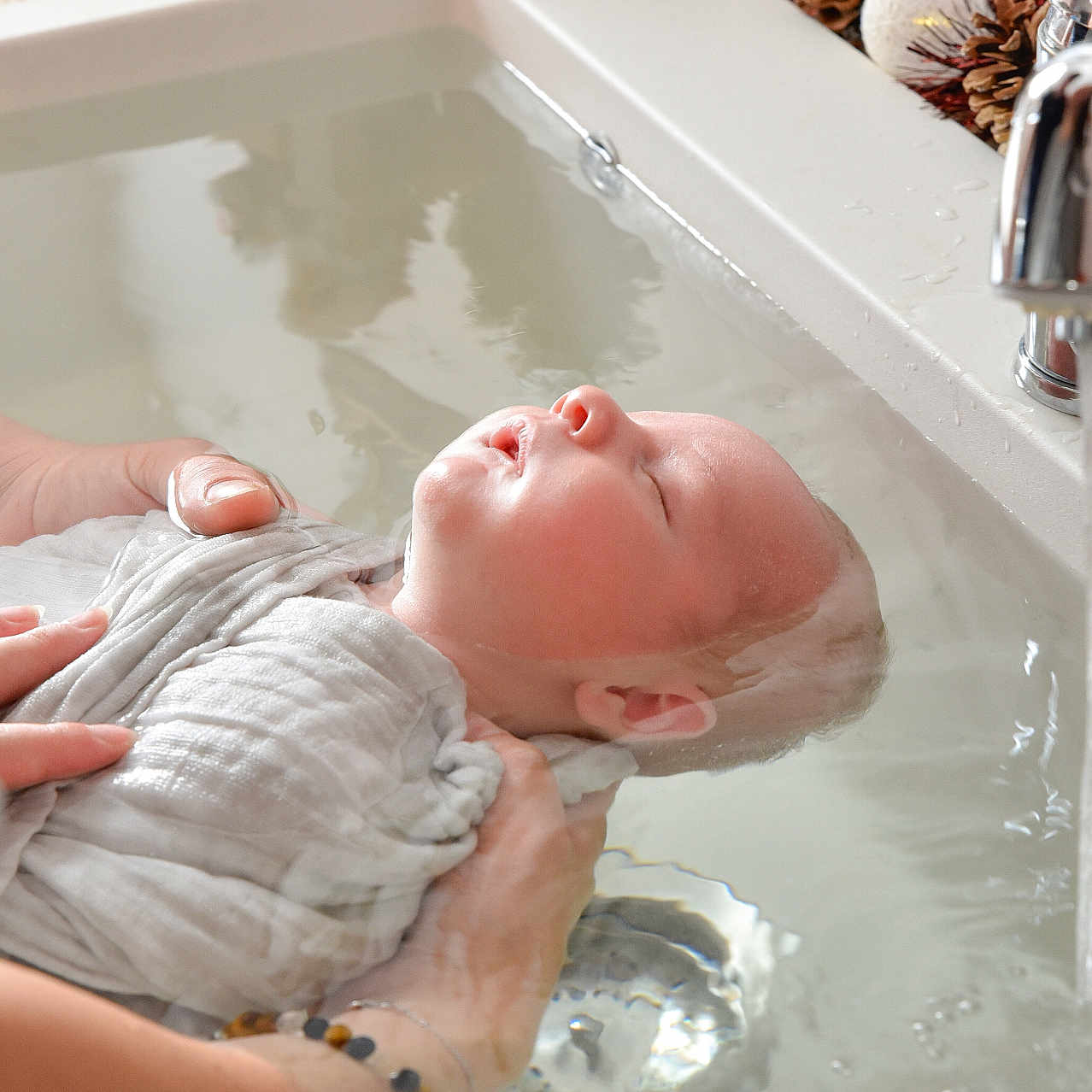 Pierre-Marie participe au concours pour gagner de l'argent avec cette photo : adult_hand, baby, bath, bathtub, christmas, closeup, decorations, face, faucet, hands, holiday, infant, peaceful, person, pinecone, relaxation, skin, sleeping, swaddle, water