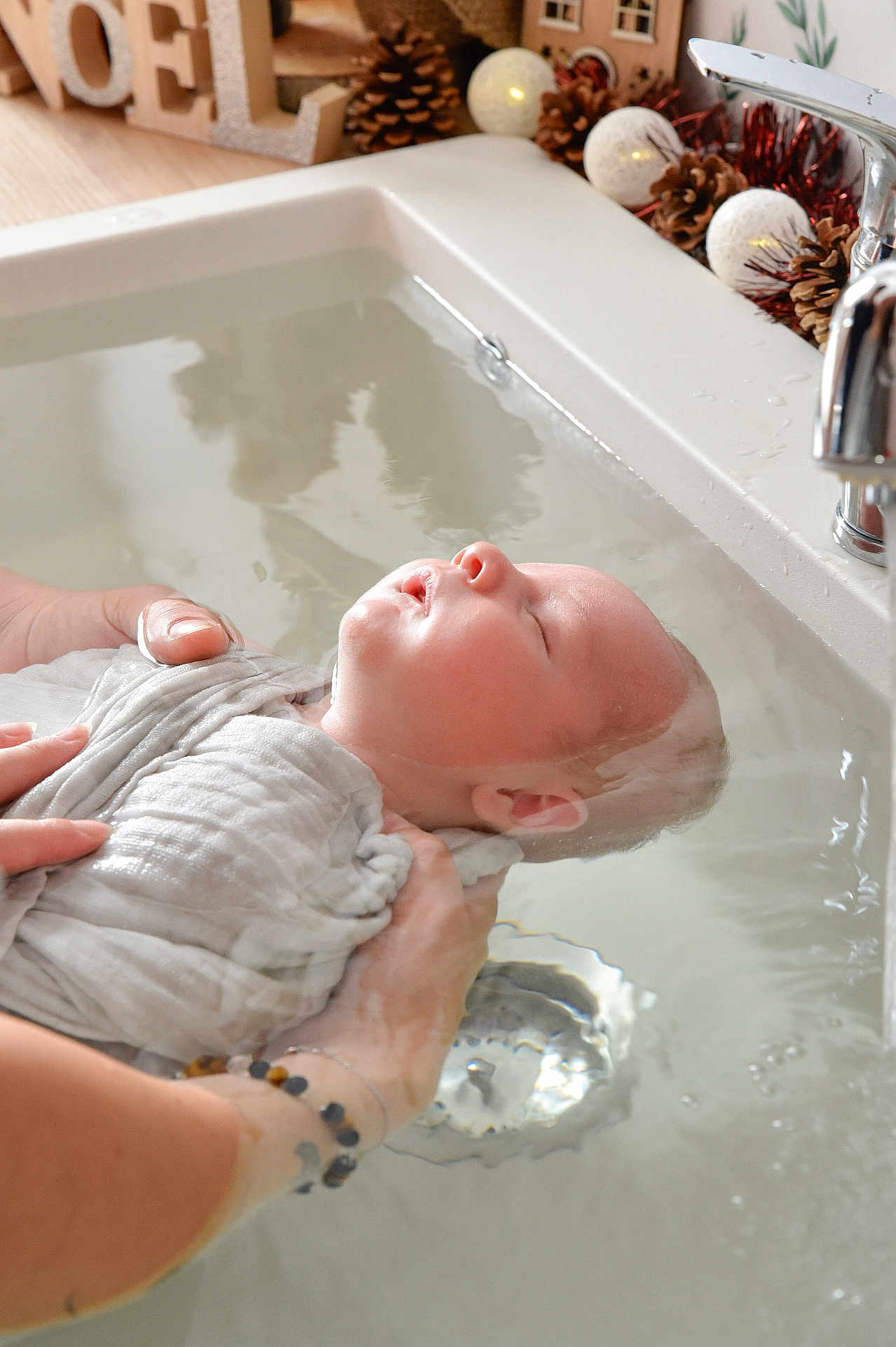 Pierre-Marie participe au concours pour gagner de l'argent avec cette photo : adult_hand, baby, bath, bathtub, christmas, closeup, decorations, face, faucet, hands, holiday, infant, peaceful, person, pinecone, relaxation, skin, sleeping, swaddle, water