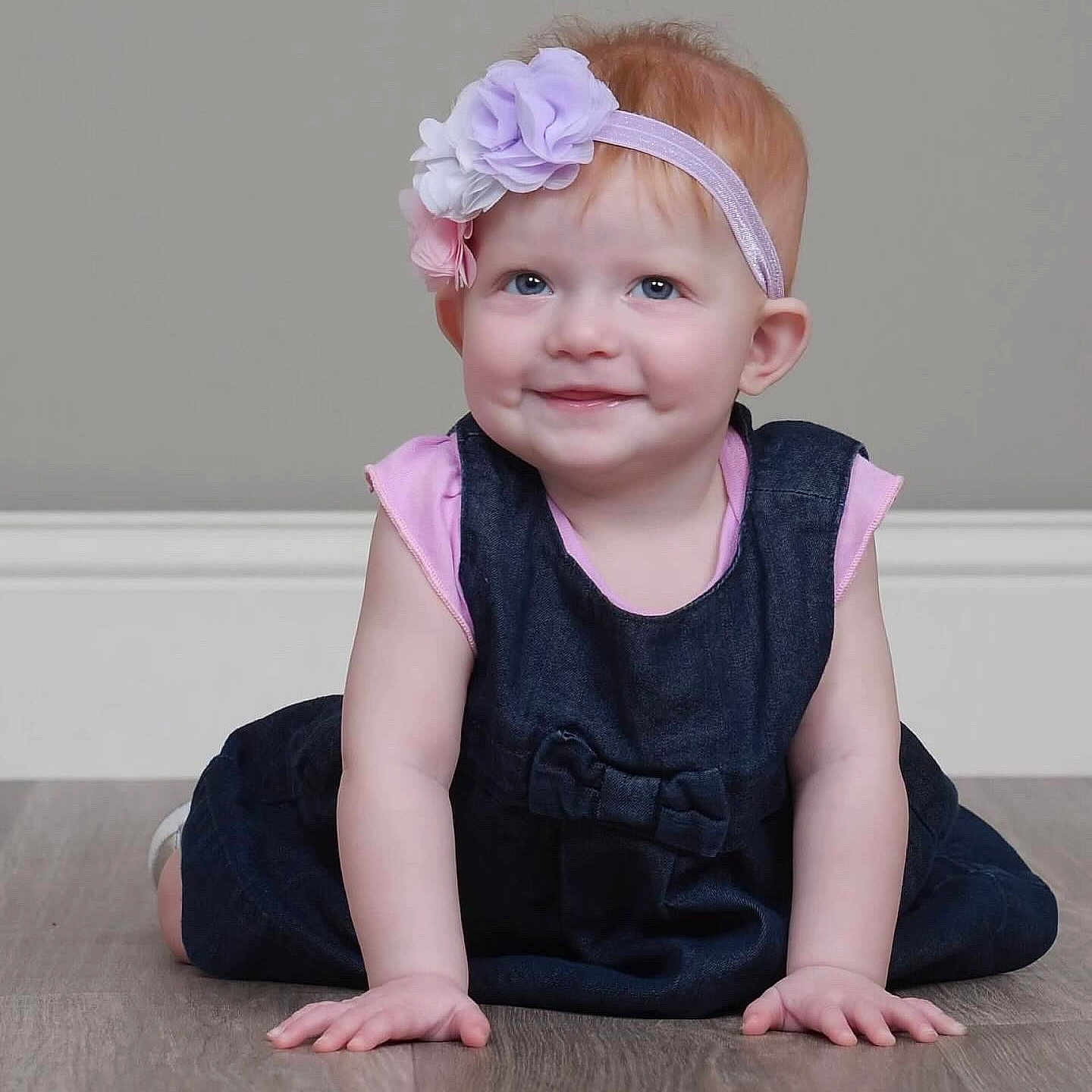Melody is registered to the contest to win money with this photo: accessories, baby, clothing, costume, dress, face, happy, hardwood, head, headband, jeans, pants, person, photography, portrait, sitting, sleeve, smile, t_shirt, wood