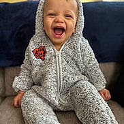 Joshua is registered to the contest to win money with this photo: toddler, child, smiling, happy, onesie, fuzzy_clothing, hooded, indoor, couch, cushion, cozy, portrait, baby, seated, cute, face, hands, living_room, warm, expression