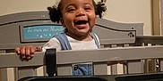 A'Zyriah joined the competition — help win amazing prizes! toddler, child, smiling, crib, indoor, hair, clothing, denim, white_shirt, hand, face, happy, baby, furniture, room, wall, sign, mesh, black, toy