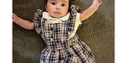 Ayzel is registered to the contest to win money with this photo: baby, infant, child, plaid_dress, headband, couch, fabric, cute, eyes, portrait, laying_down, hands, expression, indoor, person, clothing, texture, young_child, smile, sleeves