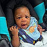 Auren is registered to the contest to win money with this photo: baby, infant, child, car_seat, blue_bib, dinosaur, blanket, hand, face, eyes, expression, clothing, seatbelt, black_padding, teal_padding, indoor, portrait, cute, person, young