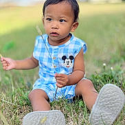 Zane is registered to the contest to win money with this photo: child, toddler, outdoor, grass, blue_clothing, mickey_mouse, sitting, nature, person, cute, summer, shoes, playing, daylight, casual, young_child, leaf, holding, curious, greenery