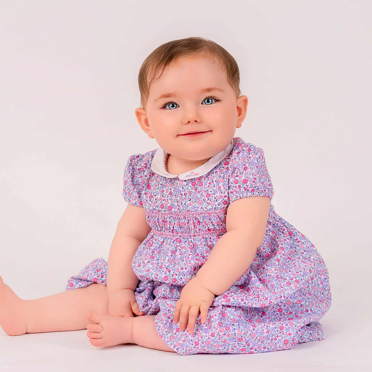 Elsie joined the competition — help win amazing prizes! baby, blue_eyes, child, cute, feet, floral_dress, hands, happy, infant, innocent, person, playful, portrait, short_hair, sitting, skin, smiling, studio, white_background, young_child