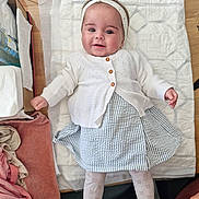 Alba participe au concours pour gagner de l'argent avec cette photo : baby, infant, child, smiling, headband, white_cardigan, striped_skirt, patterned_tights, changing_mat, wooden_surface, clothing, baby_toys, baby_items, soft_fabrics, cute, happy, portrait, indoor, person, laying_down
