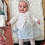 baby, infant, child, smiling, headband, white_cardigan, striped_skirt, patterned_tights, changing_mat, wooden_surface, clothing, baby_toys, baby_items, soft_fabrics, cute, happy, portrait, indoor, person, laying_down