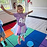 child, jumping, tutu, purple_shirt, indoor, colorful_carpet, window, playroom, happy, smiling, person, floor, light, daylight, clothing, fun, motion, kid, play, casual