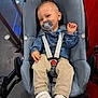 Ismaël a rejoint le concours — aidez-le/la à gagner de superbes lots ! baby, pacifier, car_seat, denim_shirt, beige_pants, white_shoes, child, infant, seatbelt, smile, indoor, floor, footwear, clothing, person, cute, happy, sitting, baby_accessory, child_seat