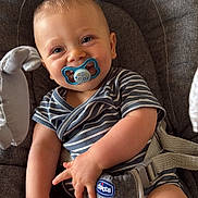 Ismaël a rejoint le concours — aidez-le/la à gagner de superbes lots ! baby, pacifier, striped_clothing, baby_chair, gray_fabric, child, infant, cute, smiling, seated, hand, legs, soft_toys, comfort, indoor, closeup, happy, chicco, onesie, playful