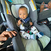 Semaj joined the competition — help win amazing prizes! baby, car_seat, child, toddler, car_interior, seatbelt, pajamas, smiling, socks, infant, hand, person, vehicle, safety_harness, cute, child_seat, automobile, young_child, happy, inside