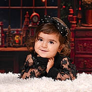 Beyna a rejoint le concours — aidez-le/la à gagner de superbes lots ! child, toddler, girl, black_dress, bow, portrait, smile, curly_hair, indoor, holiday_theme, decorations, fluffy_surface, cute, face, happy, fashion, young_child, warm_lighting, background, posing