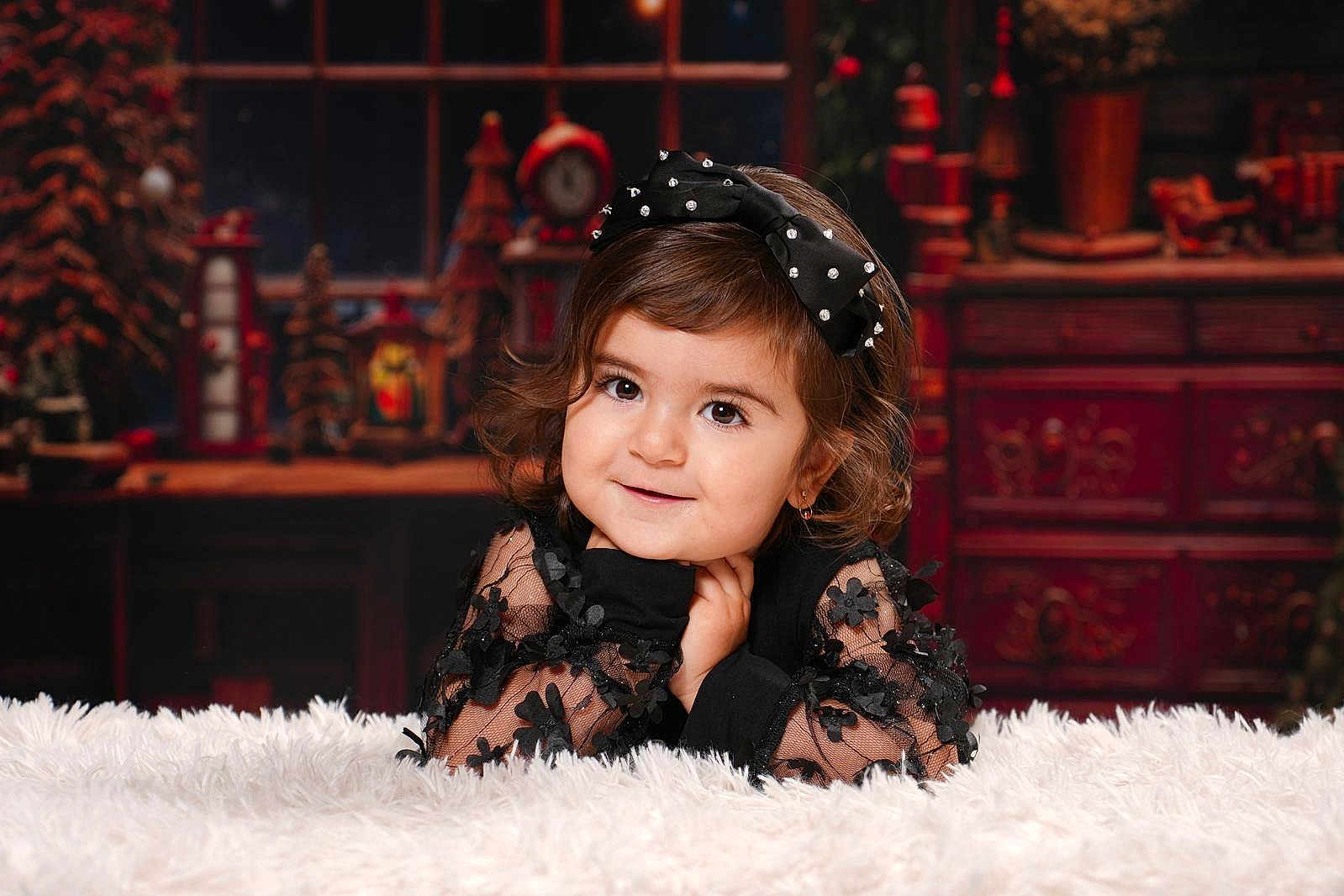 Beyna a rejoint le concours — aidez-le/la à gagner de superbes lots ! child, toddler, girl, black_dress, bow, portrait, smile, curly_hair, indoor, holiday_theme, decorations, fluffy_surface, cute, face, happy, fashion, young_child, warm_lighting, background, posing